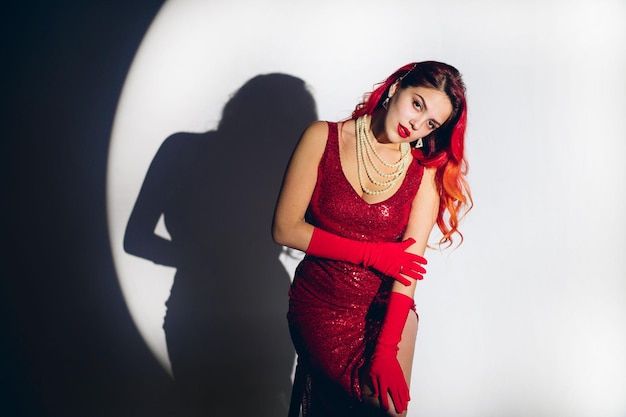 Foto la dama glamorosa con vestido rojo posa en la cámara en el fondo del estudio