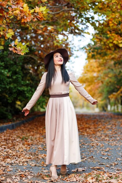 Dama graciosa caminando Mujer con vestido elegante caminando entre el colorido follaje de otoño