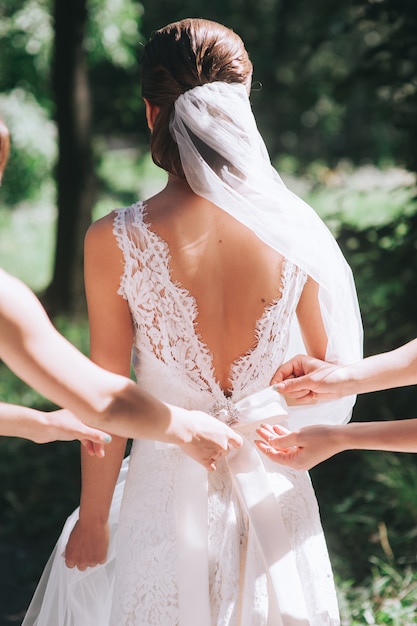 dama de honor abotonando el vestido de la novia, detalles de un hermoso vestido de novia de encaje