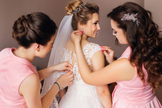 Dama de honor ayuda a la novia con su vestido