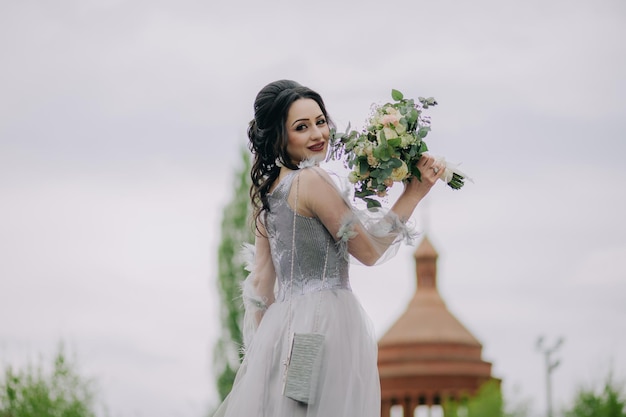 Dama de honor elegante y sonriente sosteniendo ramo de novia frente a la iglesia
