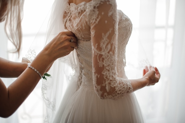 Dama de honor haciendo nudo de lazo en la parte posterior del vestido de novia