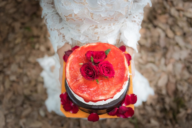 Dama de honor en un vestido blanco sosteniendo una torta de crepe