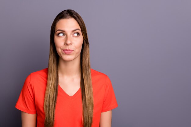 dama morena en camiseta roja posando contra la pared púrpura