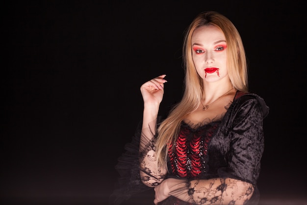 Dama de la muerte con sangre que gotea de los labios sobre fondo negro. Disfraz de Halloween.