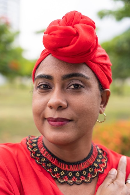 Dama negra positiva sonriendo mientras está de pie en un parque