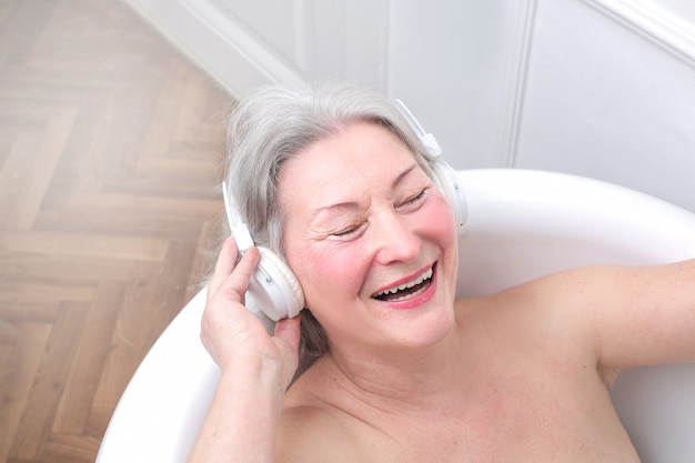 Dama senior disfrutando de un baño con música