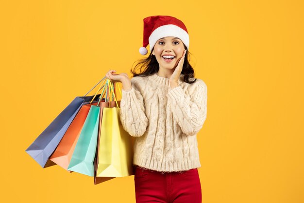 Dama sosteniendo bolsas después de la venta de Navidad de compras en fondo amarillo