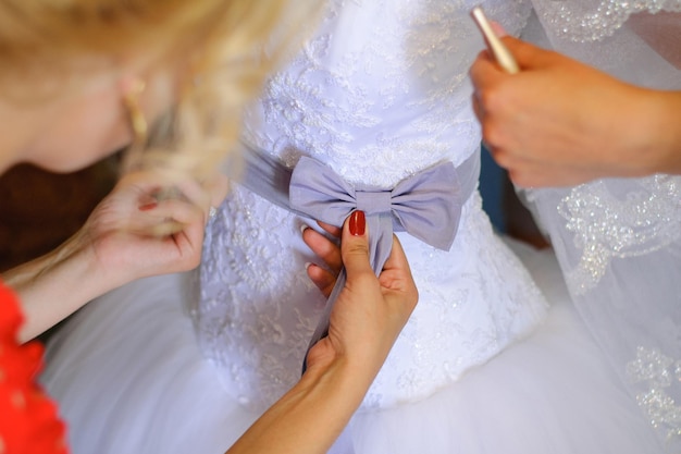 Damas de honra ajudam a noiva a vestir seu vestido de noiva