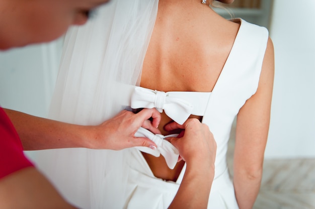 Las damas de honor ayudan a usar un vestido de novia