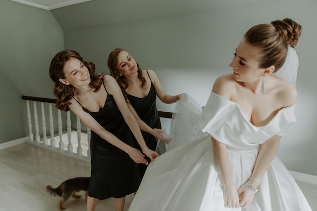 Damas de honor ayudando a la novia a ponerse el vestido de novia en el hotel