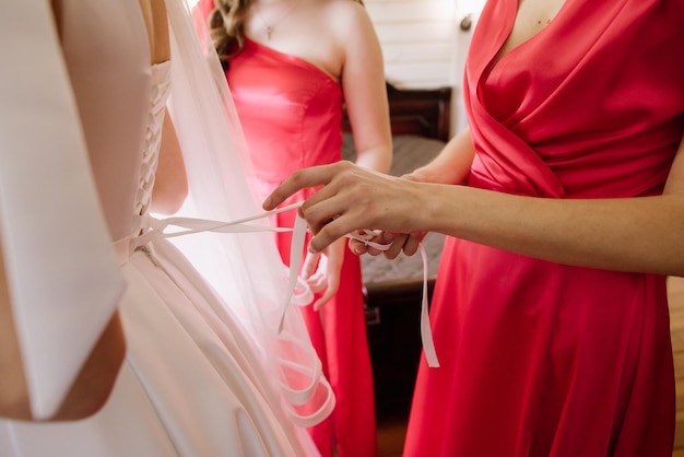 Las damas de honor visten a la novia por la mañana el día de la boda.