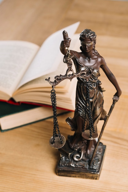 Dame der Gerechtigkeit und der Gesetzbücher auf Holztisch