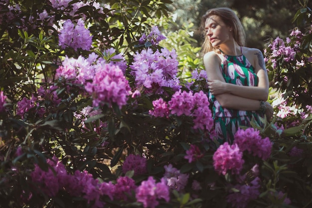 Dame, die sich in der Nähe von blühenden rosa Büschen umarmt, szenische Fotografie
