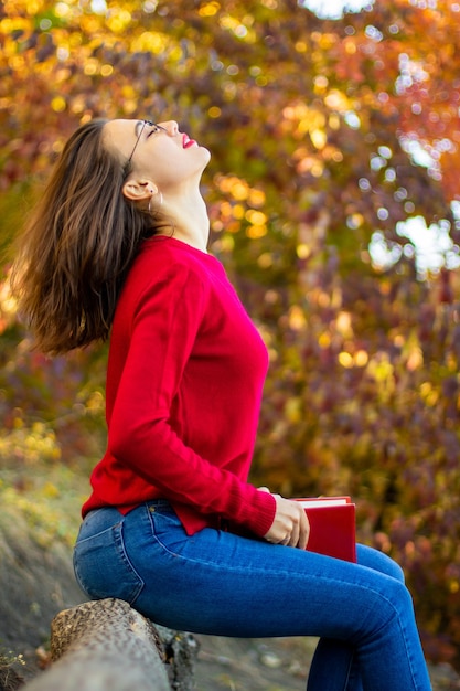 Dame im roten Pullover liest in der Natur