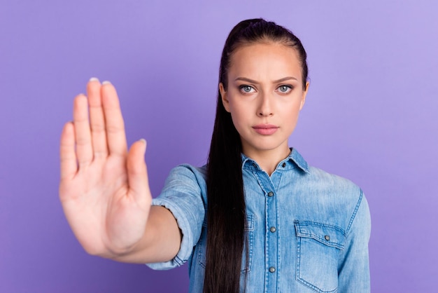 Dame macht Stopp-Geste mit ihrer Handfläche auf violettem Hintergrund