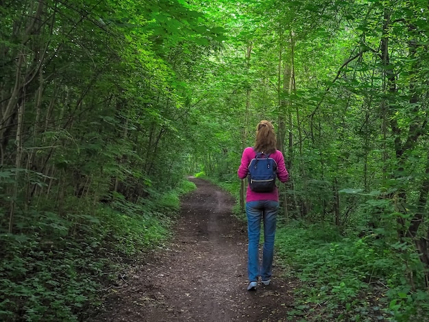 Dame mit Rucksackreise im grünen Wald.