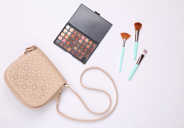 Damen-Accessoires Beauty-Produkte auf weißem Hintergrund Schminken Sie Lidschatten-Palette Make-up-Pinsel und Tasche Ansicht von oben