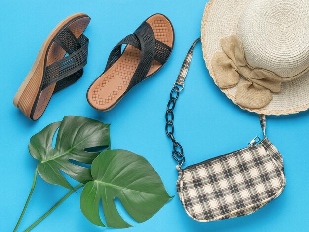 Damen Sommerschuhe Hut und Tasche auf blauem Hintergrund Das Mindestkonzept der Sommerferien