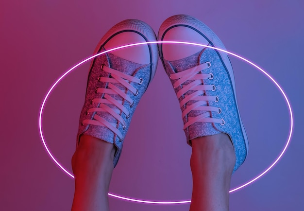 Damenfüße mit Turnschuhen. Kreative Pop-Art-Rosa-Blau-Neonfarbe. Trendige Farbverlaufsbeleuchtung. Nachtlicht