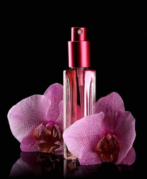 Damenparfüm in schöner Flasche und Orchideenblüten auf schwarzem Hintergrund