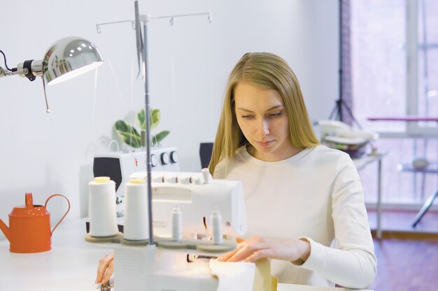 Damenschneiderinfrau, die mit Nähmaschine in der Werkstatt arbeitet