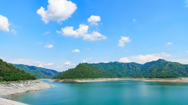 Dammansicht mit smaragdgrünem Wasser Es gibt grüne Berge und hellen Himmel