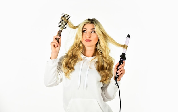 Damos-lhe o estilo Penteado com cabelo Cabelo encaracolado Usando Curling Iron Stylist curling para o penteado de cachos de mulher jovem Menina com cabelo loiro comprido soprando cabelo encaracolado feminino lindo cabelo encaracolado