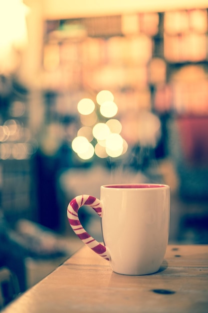 Dampfende Tasse von dir auf einem verschwommenen Hintergrund der Holztischweihnachtszeit