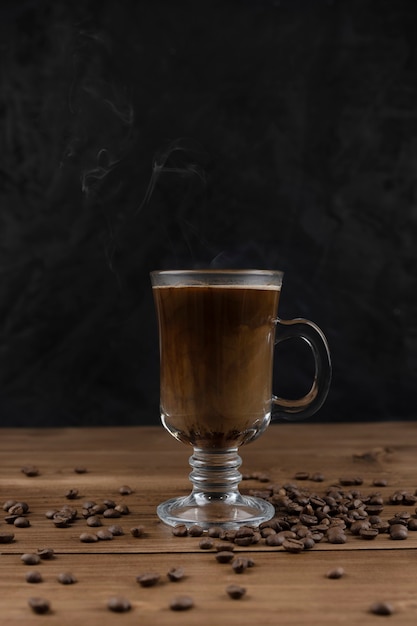 Dampfender Kaffee über Holzoberfläche und schwarzem Hintergrund.