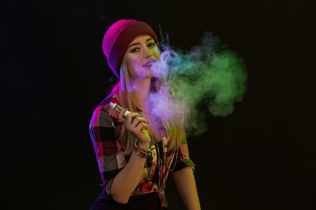 Dampfendes Mädchen. Junge Hipster-Frau vape E-Zigarette auf schwarzem Hintergrund. Hip-Hop-Stil. Studioaufnahme