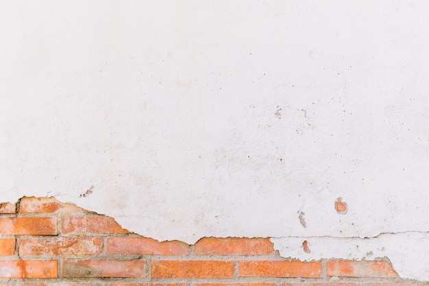 Dañado la pared de ladrillo pintado de blanco