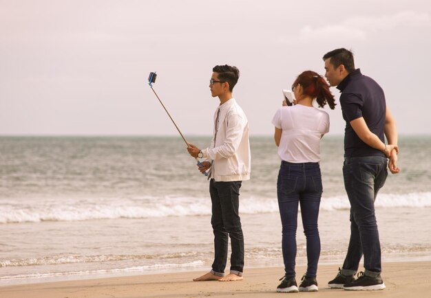 Danang, Vietnã - 20 de fevereiro de 2016: Jovens usando um bastão de selfie na praia da China, em Danang, no Vietnã