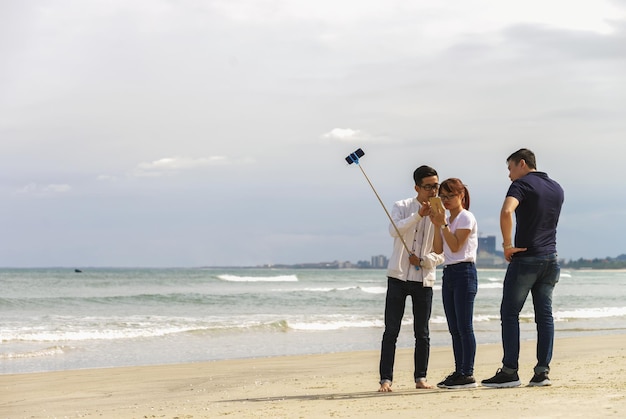 Danang, Vietnam - 20 de febrero de 2016: Los jóvenes usan un palo selfie en China Beach en Danang en Vietnam