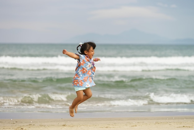 Danang, Vietnam - 20 de febrero de 2016: Niña pequeña saltando de felicidad en la playa de China en Danang en Vietnam