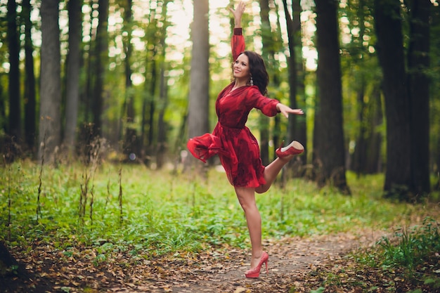 Dança bonita feliz da jovem mulher da liberdade no parque do verão com as árvores no fundo. Parque do Palácio de verão.