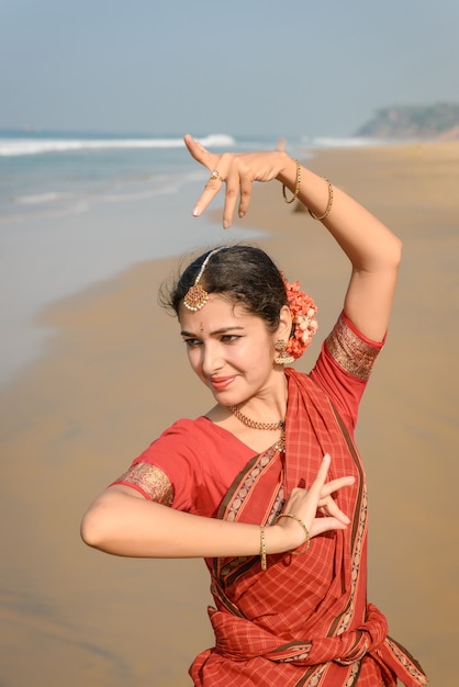 Dança clássica indiana Bharatanatyam realizada por uma mulher bonita com roupas tradicionais ao pôr do sol