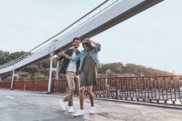 Dança despreocupada. Comprimento total de um jovem casal brincalhão de mãos dadas e girando