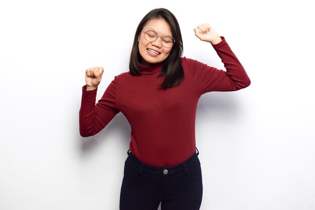 Dança e felicidade de jovens lindas mulheres asiáticas vestem camisa vermelha isolada no fundo branco