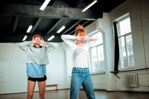 Dança expressiva. a bela professora ruiva de jeans e uma aluna de short preto passando um tempo em um estúdio de dança