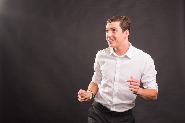 Dança, felicidade, conceito de pessoas - homem bonito na camisa branca dançando sobre o fundo cinza com espaço de cópia.