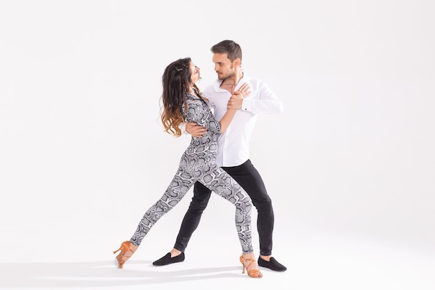 Dança social, bachata, kizomba, zouk, conceito de tango - homem abraça mulher enquanto dança sobre fundo branco com espaço de cópia