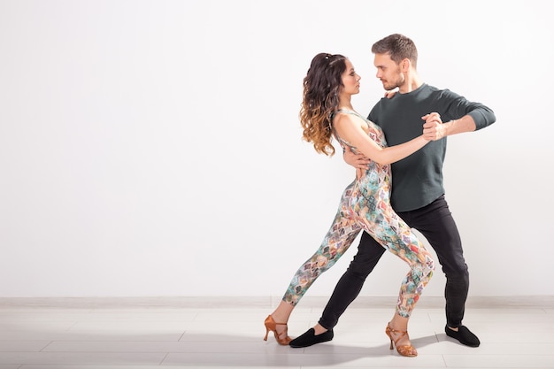 Dança social, bachata, salsa, kizomba, zouk, conceito de tango - Homem abraça mulher enquanto dança sobre o branco