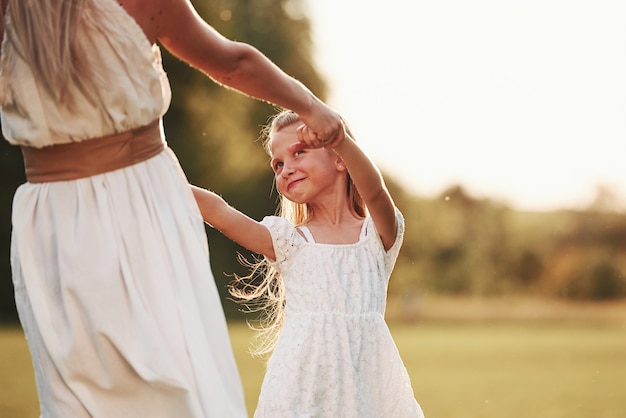 Dançando em círculos. Mãe e filha aproveitando o fim de semana juntos, caminhando ao ar livre no campo. Natureza bela.