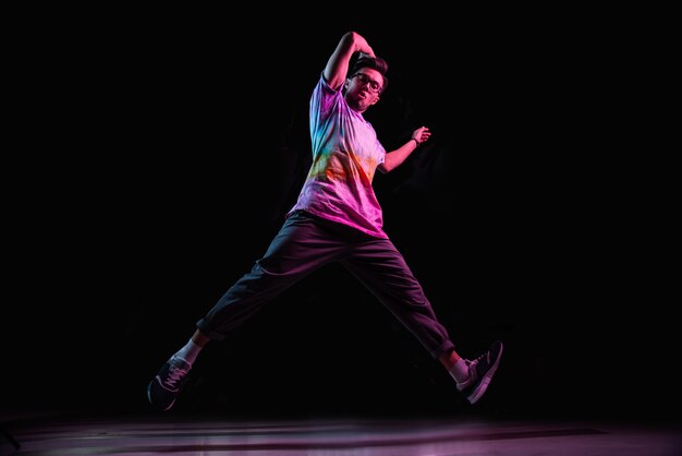 Dançarina break profissional pulando, praticando a dança hip-hop moderna em luz de néon rosa