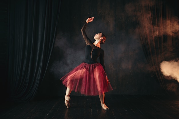 Dançarina de balé com vestido vermelho dançando no palco no teatro. Bailarina graciosa treinando na aula