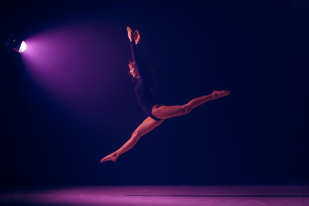 Dançarina de balé feminino jovem dançando no fundo do estúdio de luzes de néon. Projeto de bailarina com modelo caucasiano. O balé, dança, arte, contemporâneo, conceito de coreografia