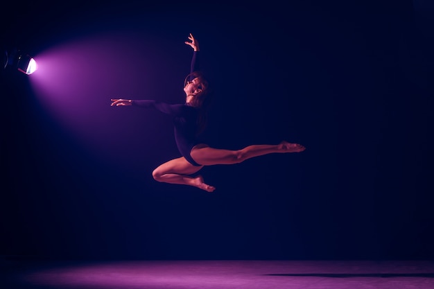 Dançarina de balé feminino jovem dançando no fundo do estúdio de luzes de néon. Projeto de bailarina com modelo caucasiano. O conceito de balé, dança, arte, contemporâneo, coreografia