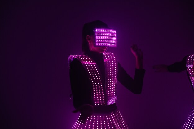 Dançarina de discoteca sexy dançando em um traje ultravioleta ao som de música. Festas e danças.