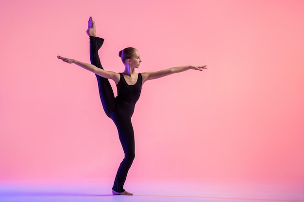 Dançarina de jovem adolescente dançando sobre um fundo vermelho do estúdio. Balé, dança, arte, modernidade, conceito de coreografia